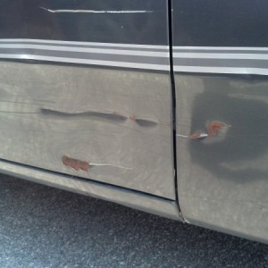 Dents, cuts, and rust on passenger side door.